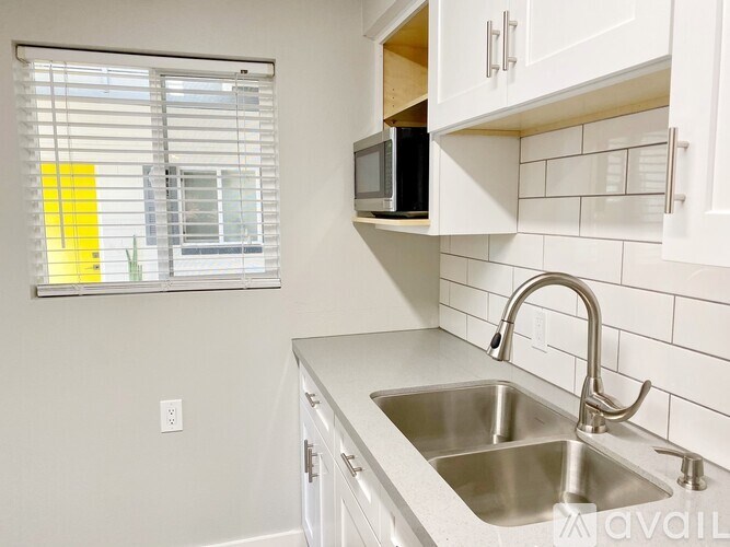 A kitchen with a stainless steel sink and a window with blinds.