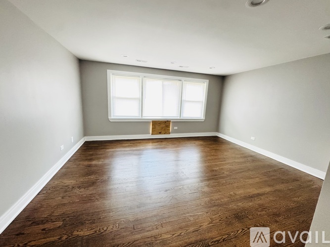 A spacious room with wooden flooring and a window.