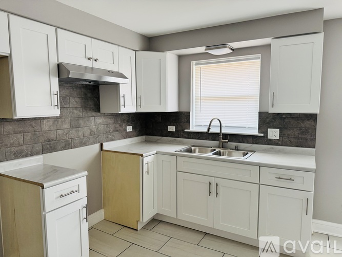 A kitchen with white cabinets and a black countertop.