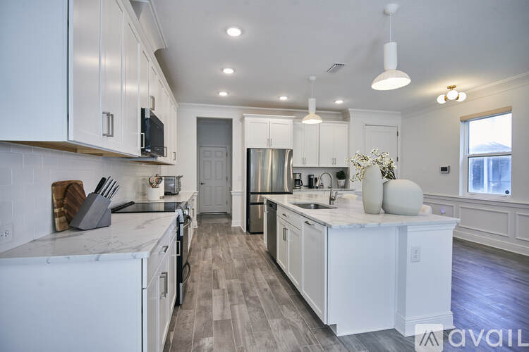 A kitchen with white cabinets and a marble countertop.