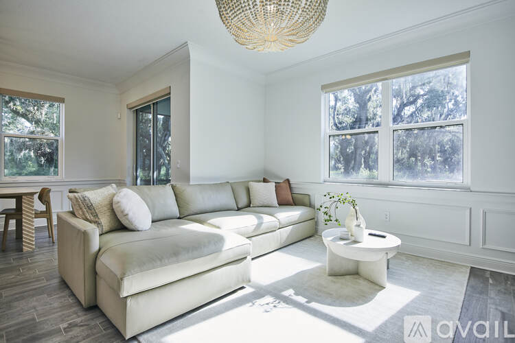 A living room with a white couch and a woven light fixture.