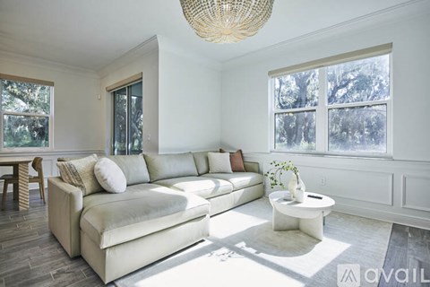 A living room with a white couch and a woven light fixture.