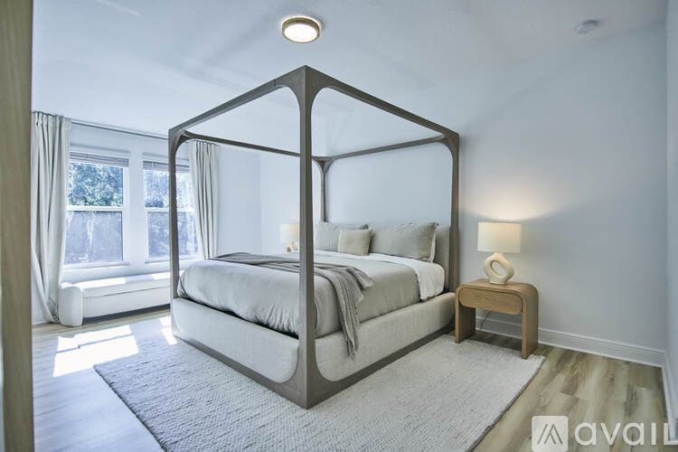 A bedroom with a large bed and a window with curtains.
