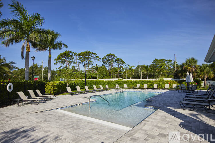 A pool surrounded by lounge chairs and palm trees.