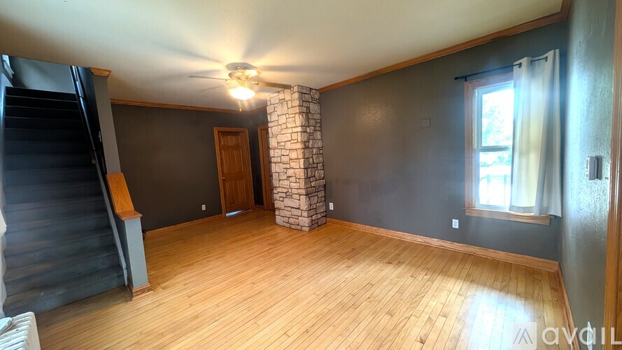 A room with wooden floors and a stone pillar.