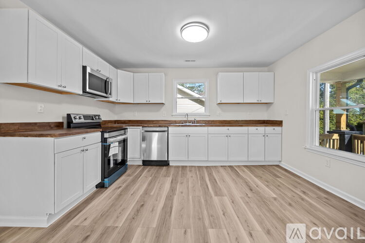 A kitchen with white cabinets and wooden floors.