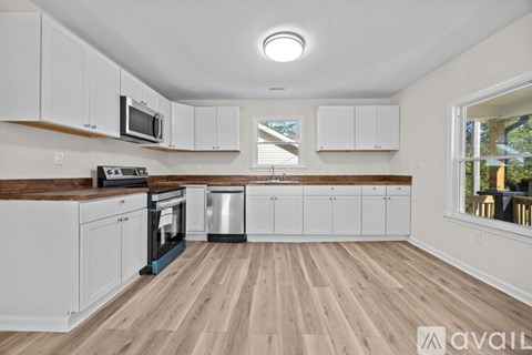 A kitchen with white cabinets and wooden floors.