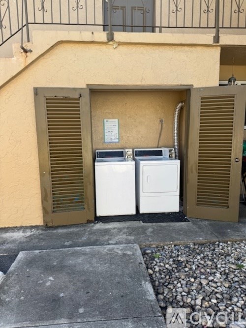 Two washing machines are placed in front of a yellow wall.