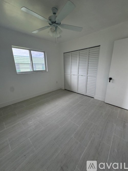A room with a ceiling fan and a window with blinds.