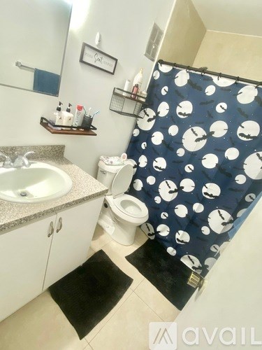 A bathroom with a sink, toilet, and shower curtain.