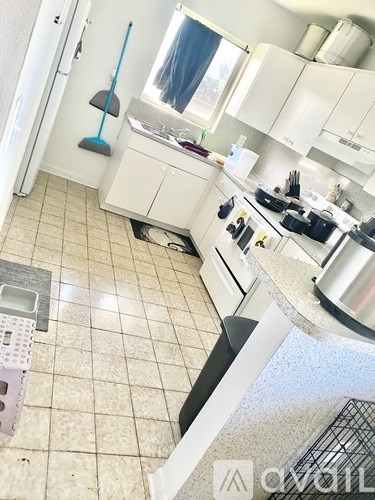 A kitchen with white cabinets and a tiled floor.