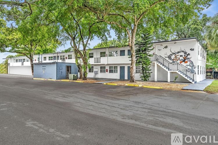 A building with a mural on the side is surrounded by trees.