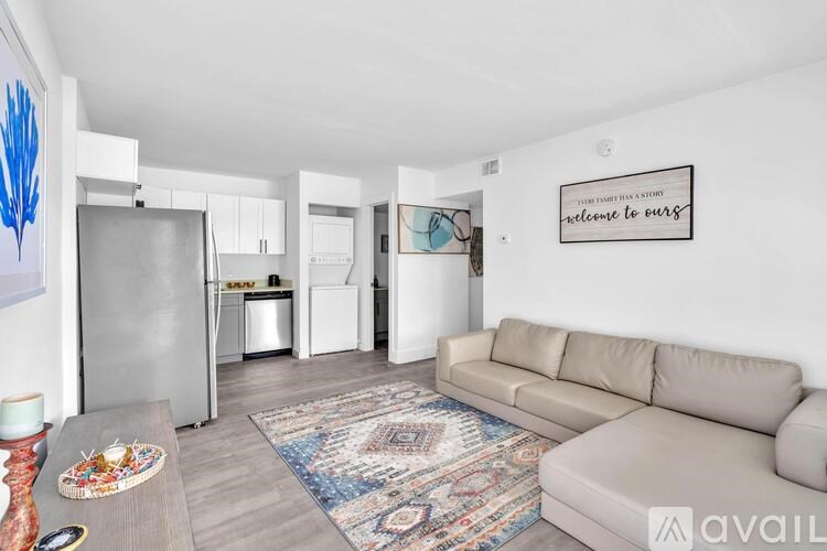 A living room with a couch, rug, and a framed sign on the wall.