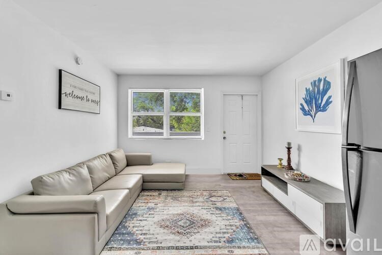 A living room with a beige couch, a rug, and a framed picture on the wall.