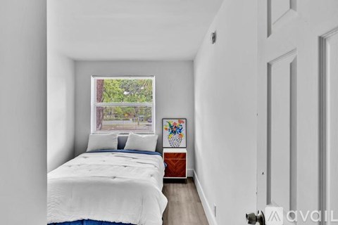 A bedroom with a large bed and a window overlooking a garden.