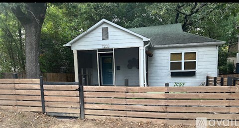 A small white house with a brown fence in front of it.