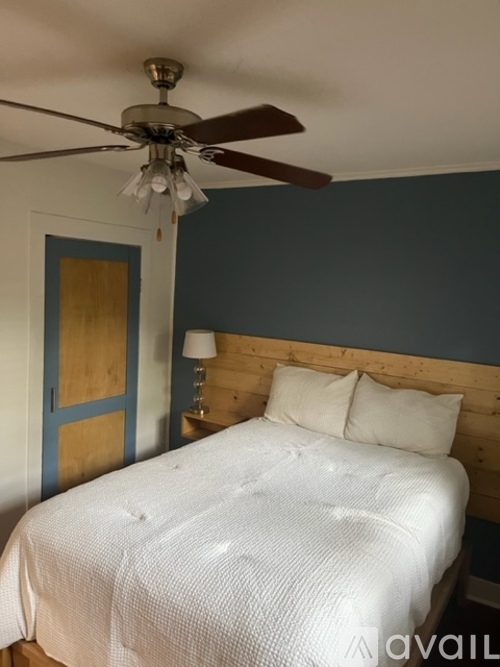 A bedroom with a white bed and a ceiling fan.