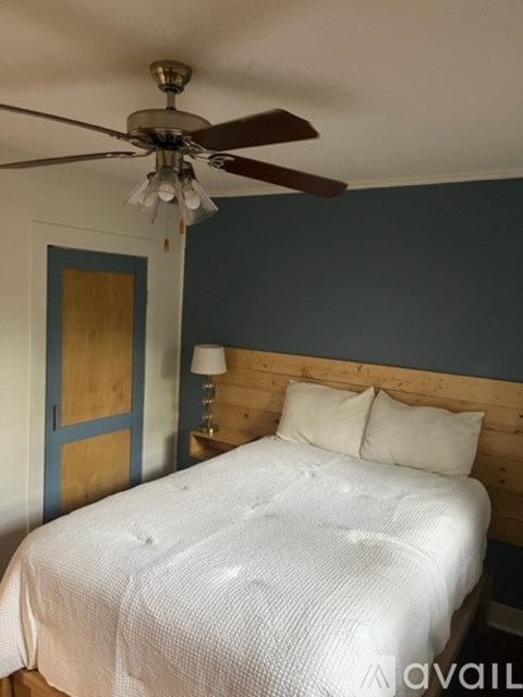 A bedroom with a white bed and a ceiling fan.
