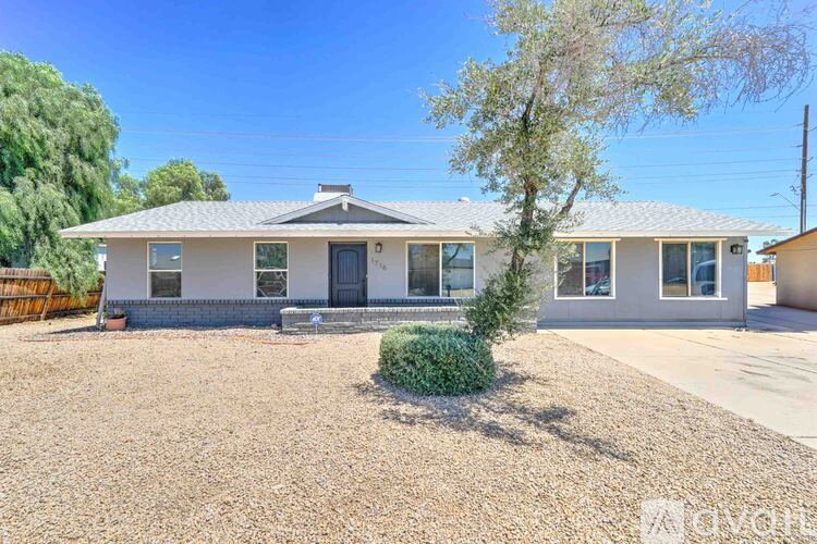 A house with a gravel driveway and a small tree in front.