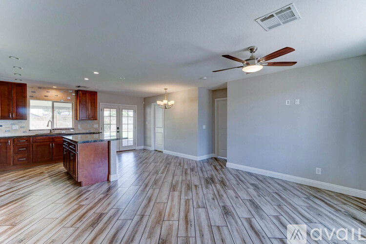 A spacious room with wooden flooring and a ceiling fan.