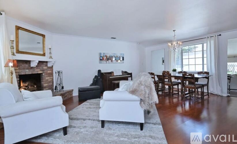 A living room with a fireplace, a couch, a chair, and a dining table.