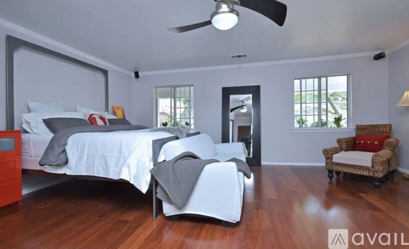 A bedroom with a bed, chair, and ceiling fan.