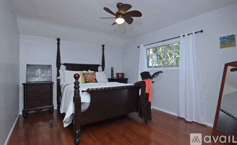 A bedroom with a four poster bed and a ceiling fan.