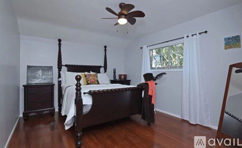 A bedroom with a four poster bed and a ceiling fan.