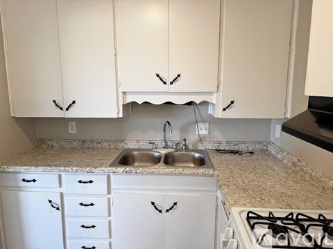 A kitchen with white cabinets and a granite countertop.