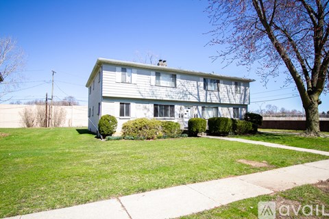 A house with a green lawn and a tree in front.