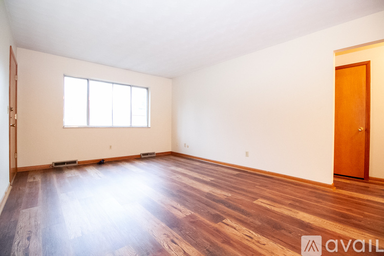 A room with wooden floors and a window is available for rent.