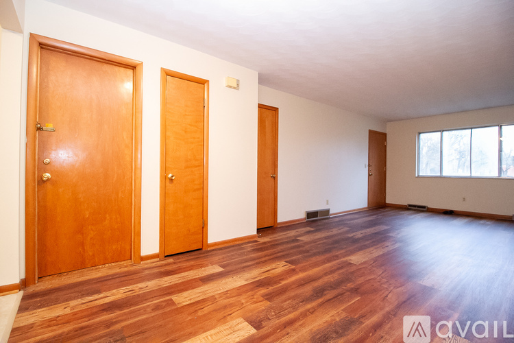 Three wooden doors in a room with wooden flooring.
