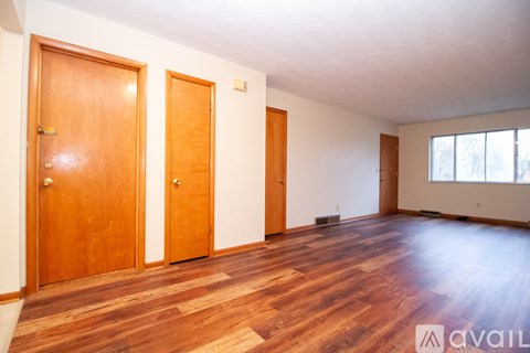 Three wooden doors in a room with wooden flooring.