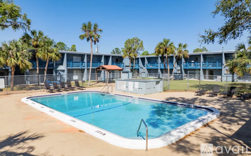A pool surrounded by palm trees and a building in the background.
