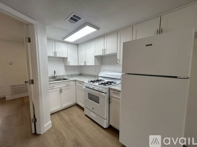 A kitchen with white appliances and cabinets.