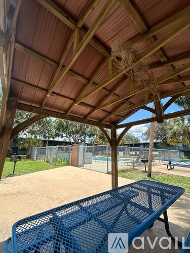 A blue picnic table is under a wooden shelter.