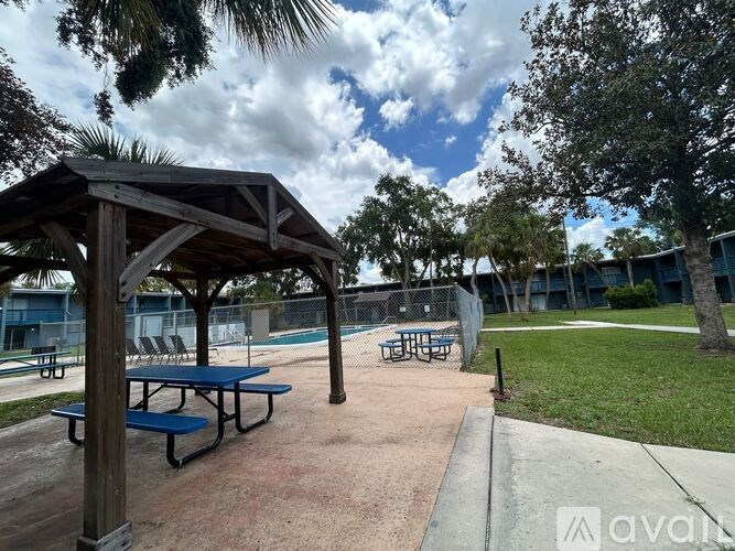 A pavilion with blue benches is surrounded by trees.