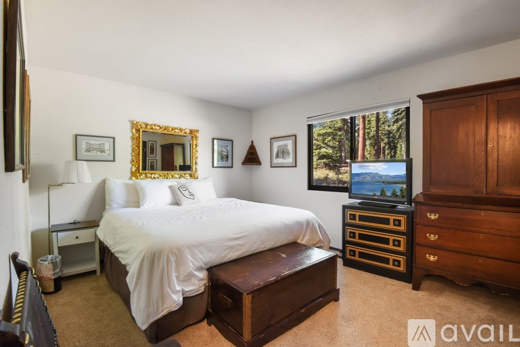A bedroom with a large bed, a wooden dresser, and a TV.