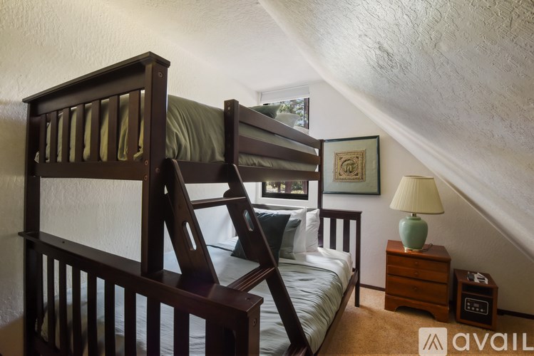 A bedroom with a bunk bed and a nightstand with a lamp.