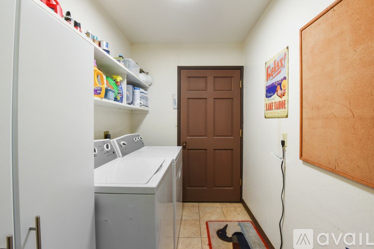 A small kitchen with a refrigerator, washing machine, and a wooden door.