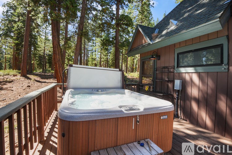 A hot tub is on a deck in the woods.