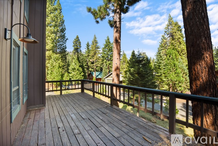 A wooden deck with a lamp and a railing overlooking a forest.