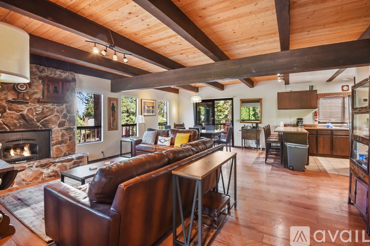 A living room with a stone fireplace and wooden floors.