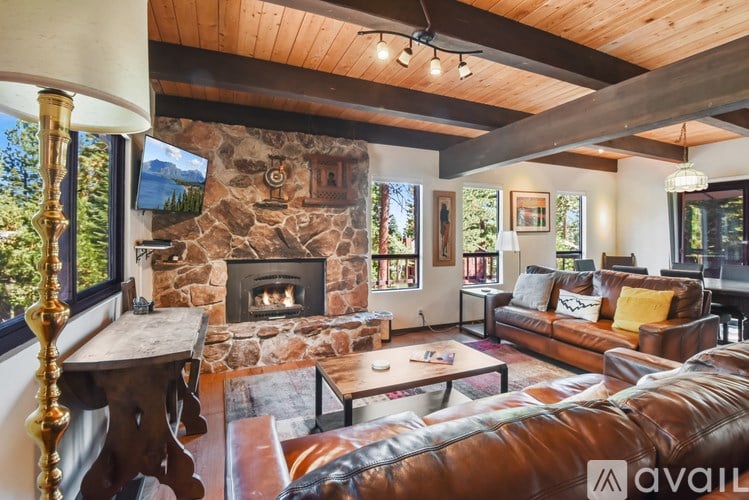 A living room with a stone fireplace and leather couches.