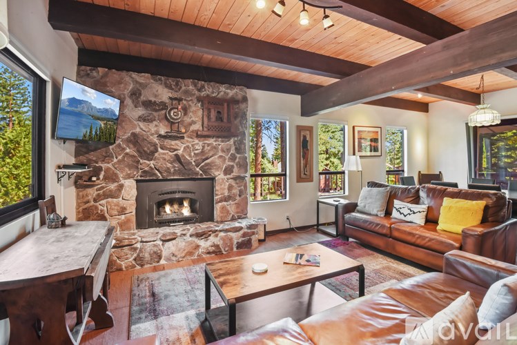 A living room with a stone fireplace and a flat screen TV mounted on the wall.
