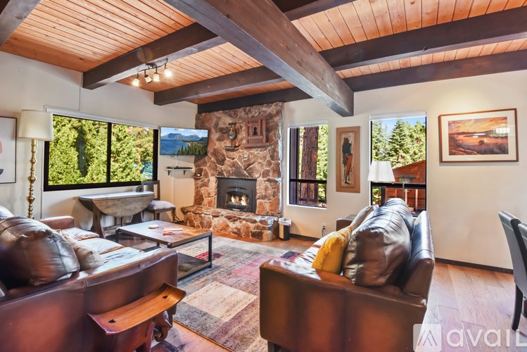 A living room with a stone fireplace and a large window.