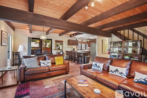 A living room with a brown leather couch and a wooden ceiling.