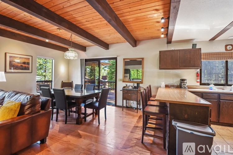 A wooden table is surrounded by chairs in a room with a couch and a dining table.