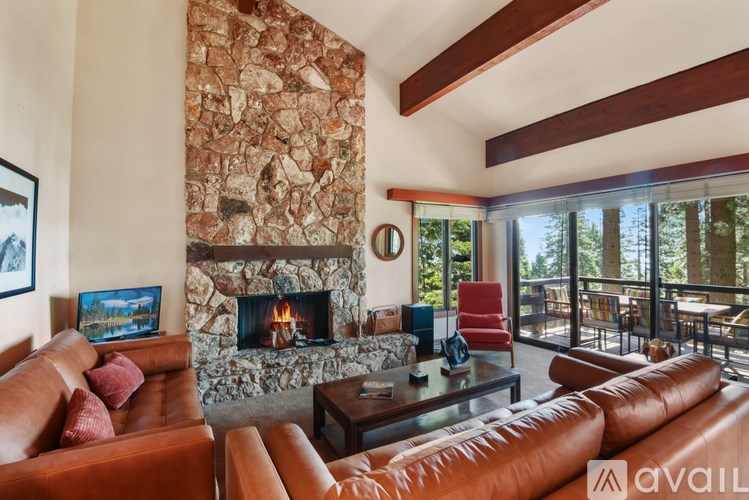 A living room with a stone fireplace and leather couches.