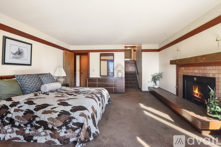 A bedroom with a fireplace and a bed with a floral comforter.